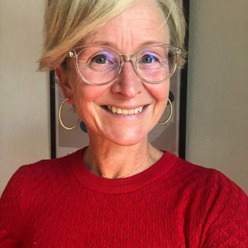 Lyshåret kvinde o rød bluse der smiler